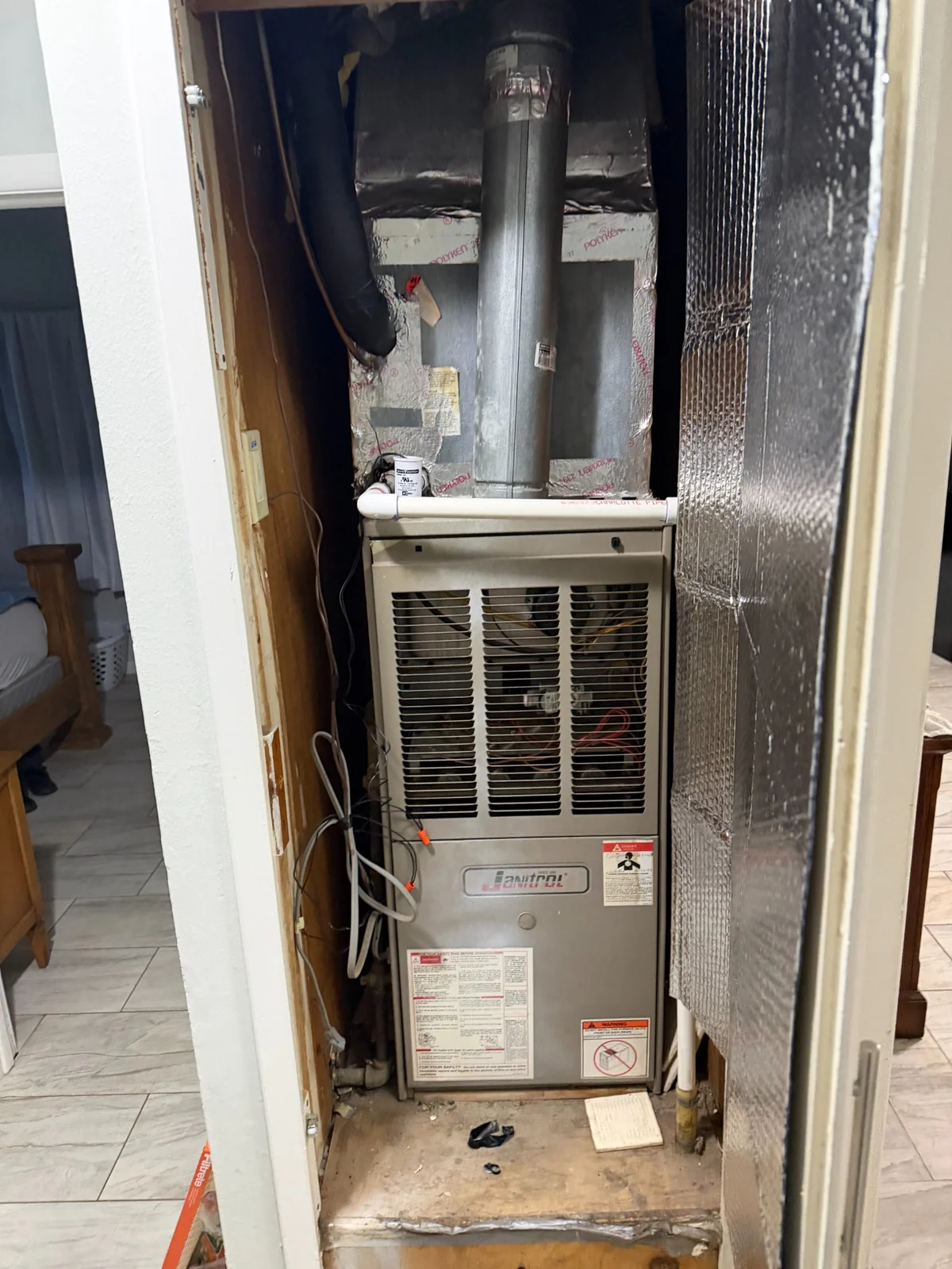 Before photo showing the older furnace and closet setup before replacement
